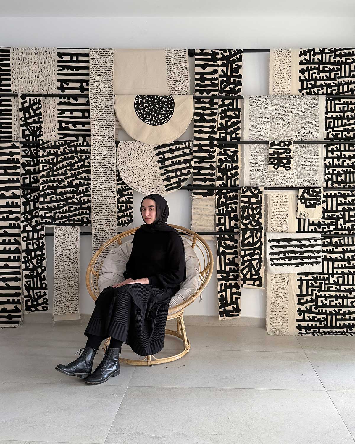 Mariem Abutaleb sits in front of her artwork