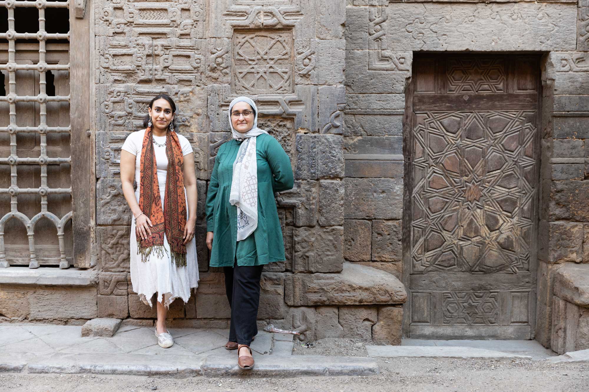 Yumna Moussa and Ehsan Abushadi stand in front of a heavily patterned building in historic Cairo