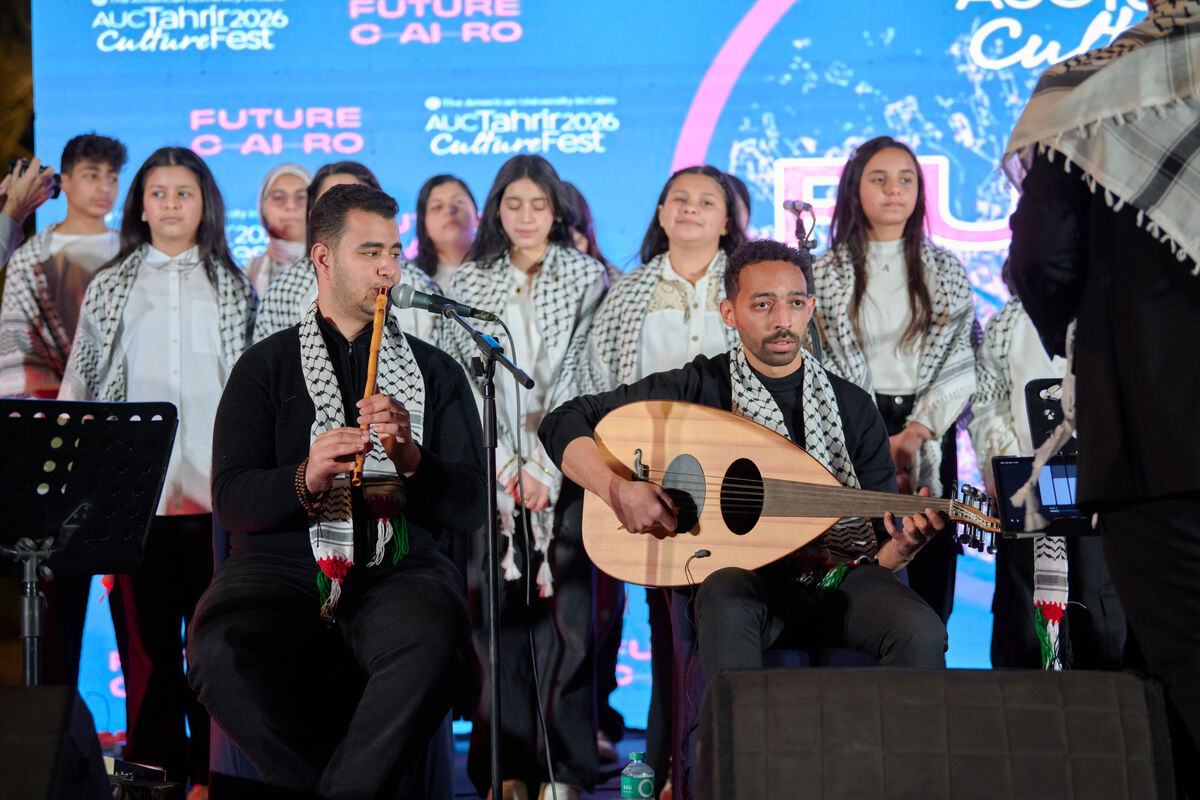 Two musicians play the ney and oud on stage and a choir of children sing behind them