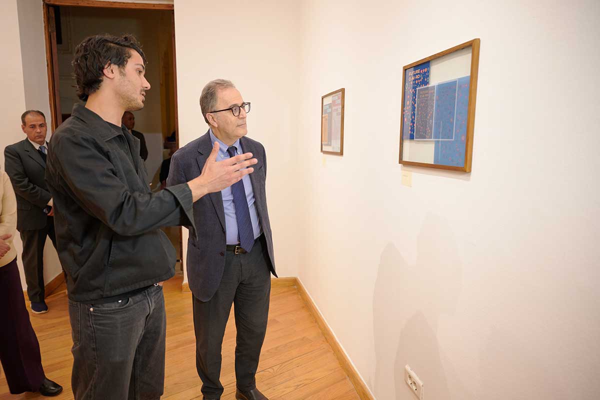 AUC president Ahmed Dallal and a person observe an art piece hanging on the wall
