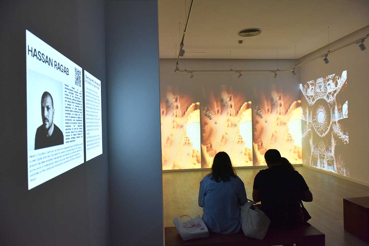 Two people watch a wall projection in a art gallery