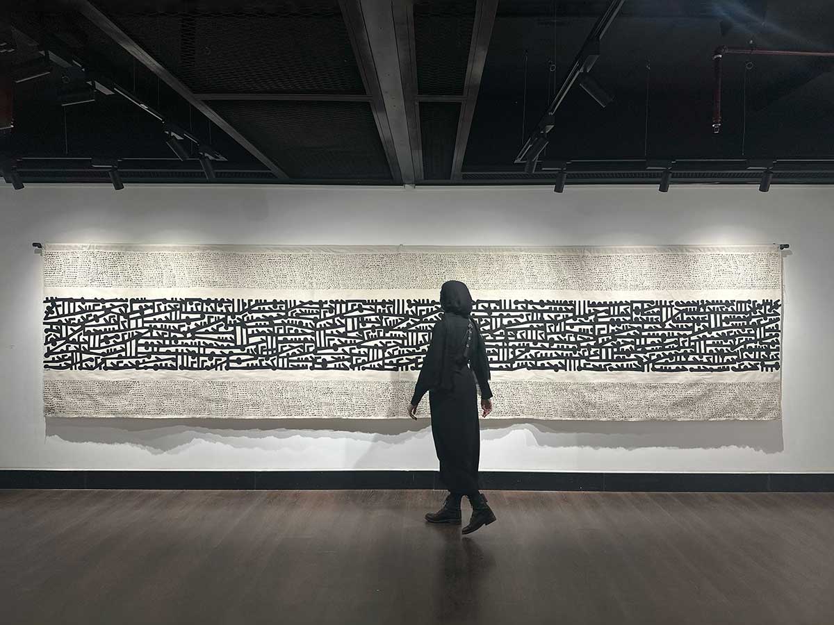 Mariem Abutaleb walks in front of her art in a gallery artwork