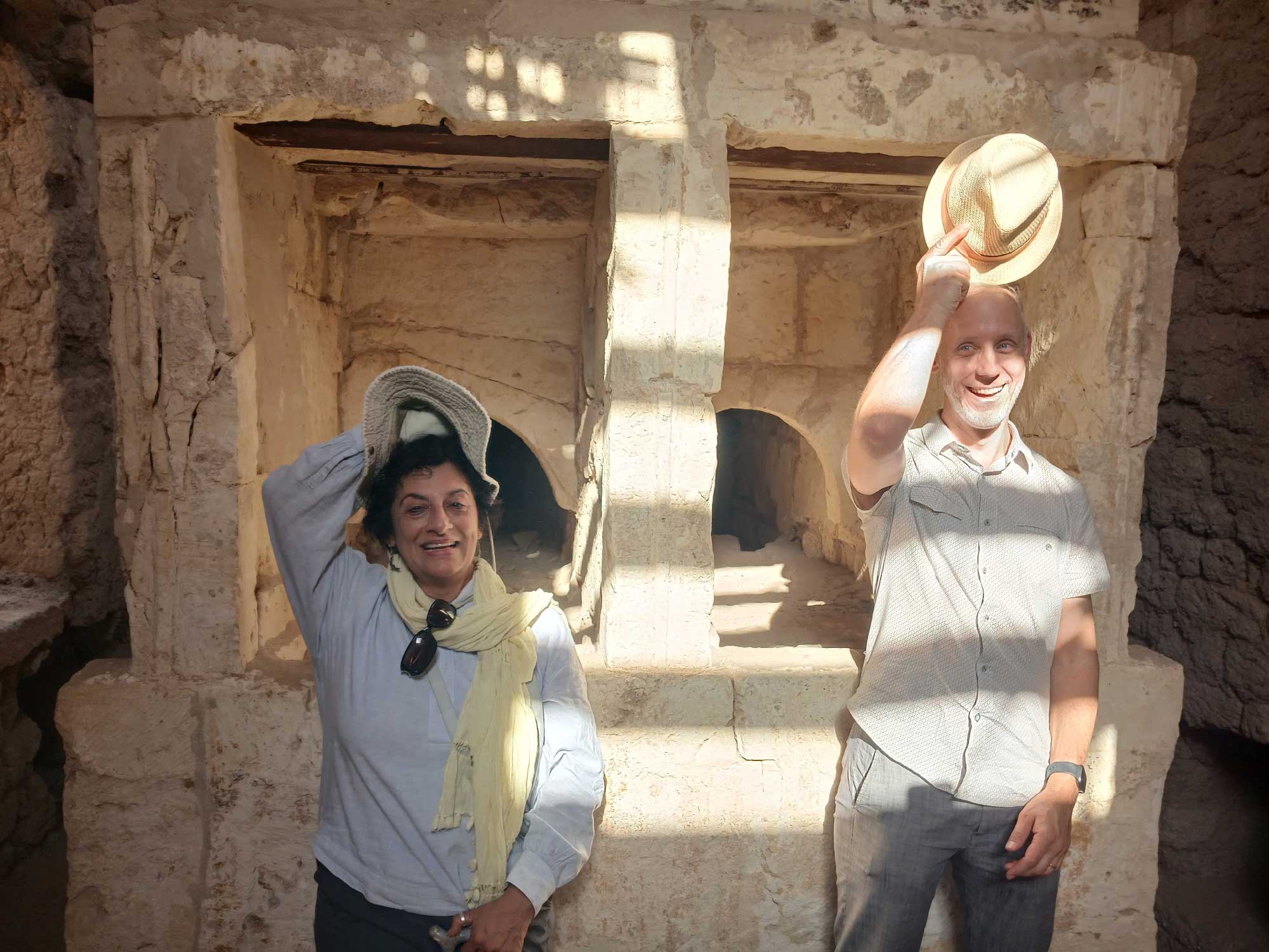 A woman and man stand in Fayoum holding hats.