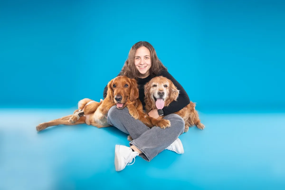 Woman poses with two golden retrievers