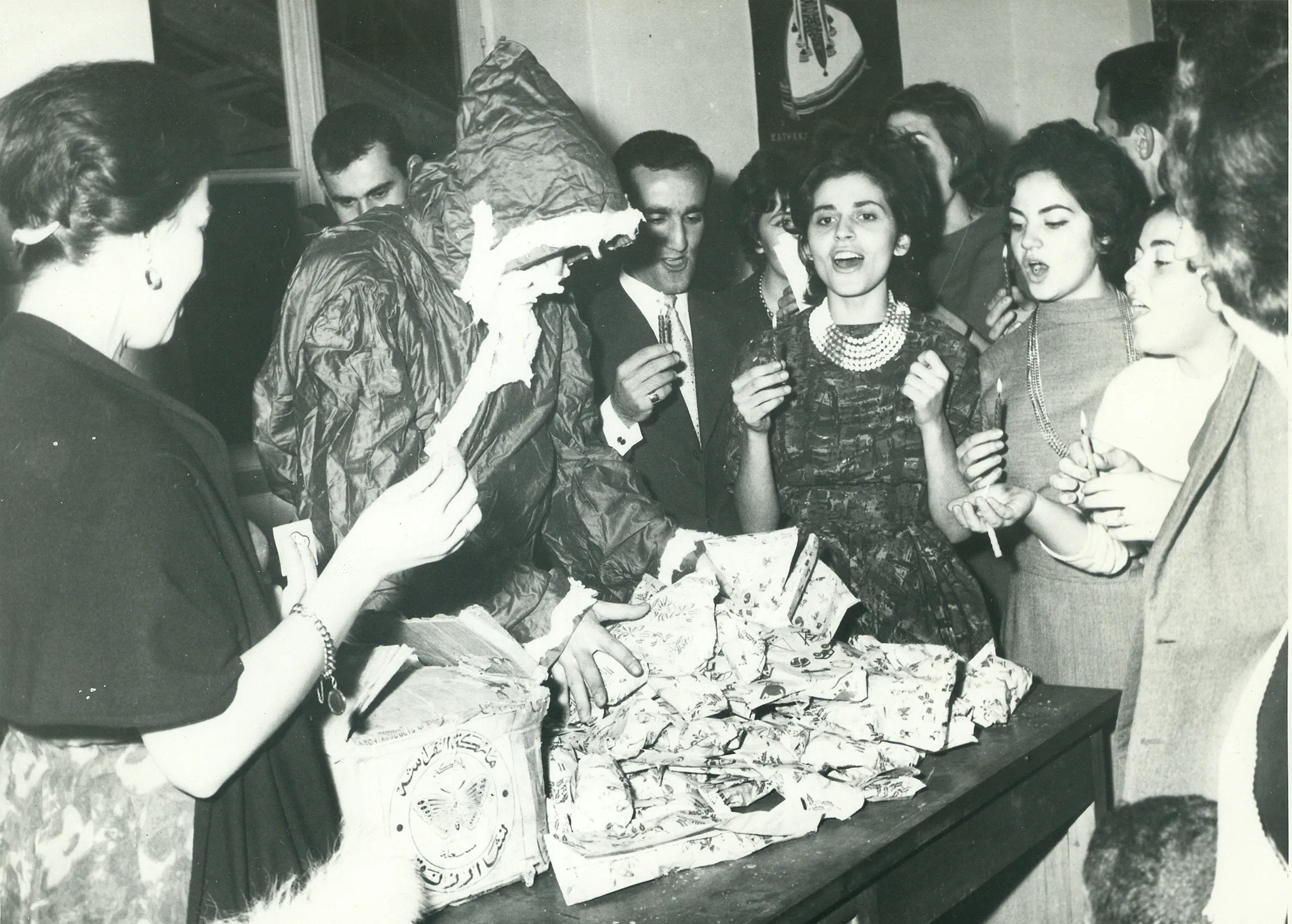 black and white photo of man wearing a santa costume standing over a table of food