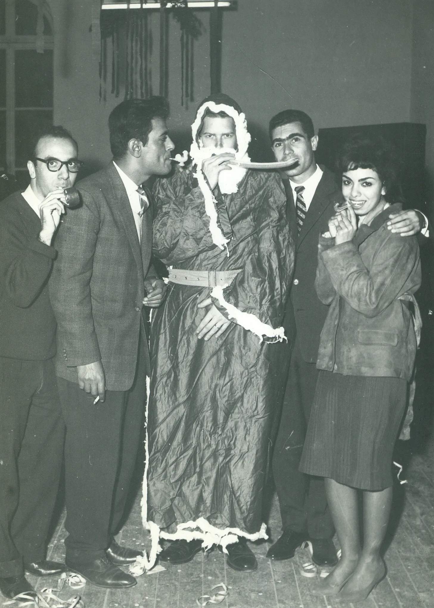 black and white photo of man wearing a santa costume with other people standing next to him 