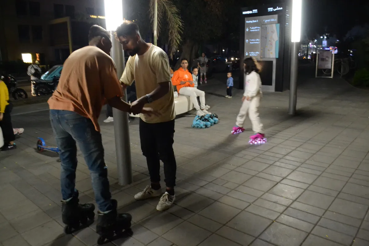 two people wearing roller skates hold hands while other skaters skate behind them