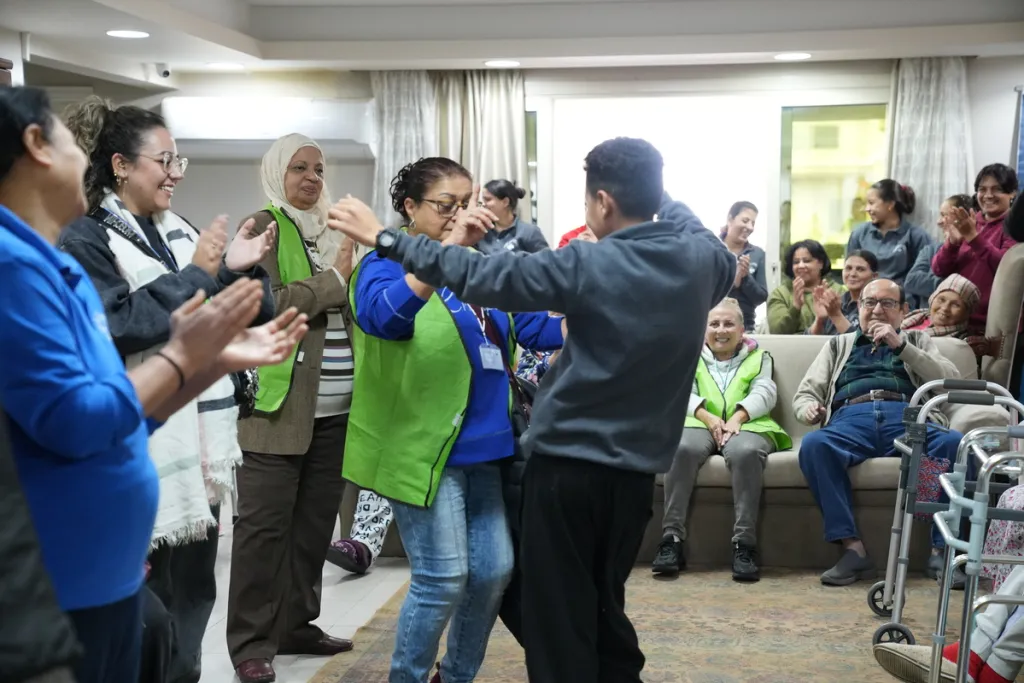 an old person and a young person dancing together at a retirement home