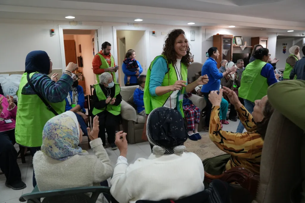 group of people standing and sitting inside a room clapping and/or dancing to music
