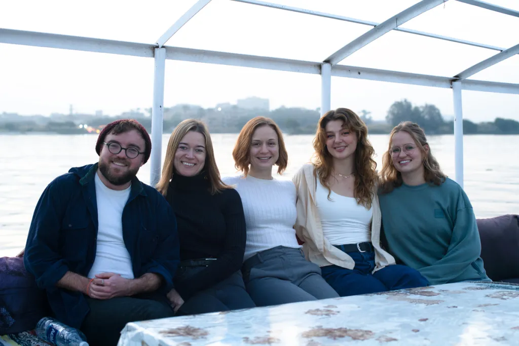 five people smile while sitting on a felucca on the Nile in Cairo, Egypt