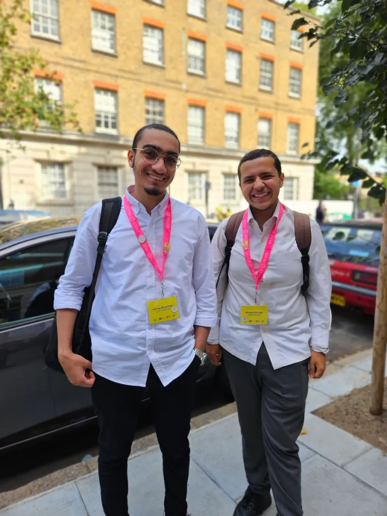 two men standing on a street in front of a brick building in London