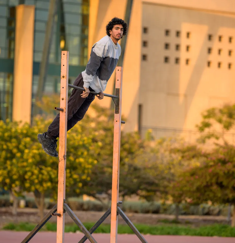 man balancing on a pull up bar outside