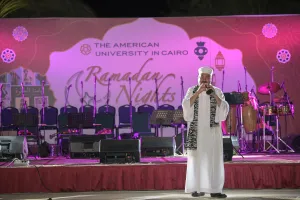A man in a white galabeya plays the flute on stage.