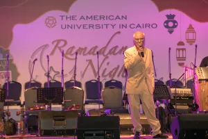 Man with microphone and tan suit speaking into a microphone