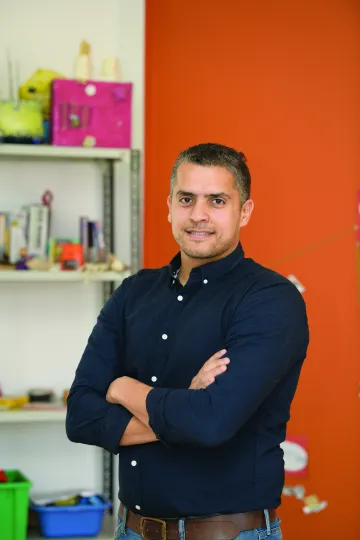 A man poses with his arms crossed, smiling