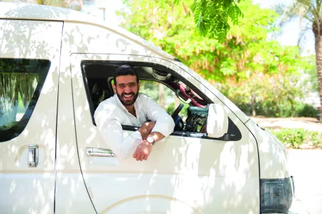 A smiling man leans out of a bus window.
