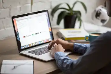 a laptop open with a person's hands resting on the keyboard