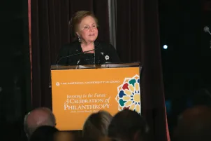 A woman stands at a podium making a speech