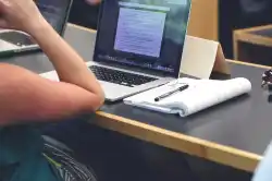 a generic photo of a laptop and notebook with a hand