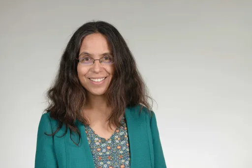 Woman wearing glasses and a green blazer smiling