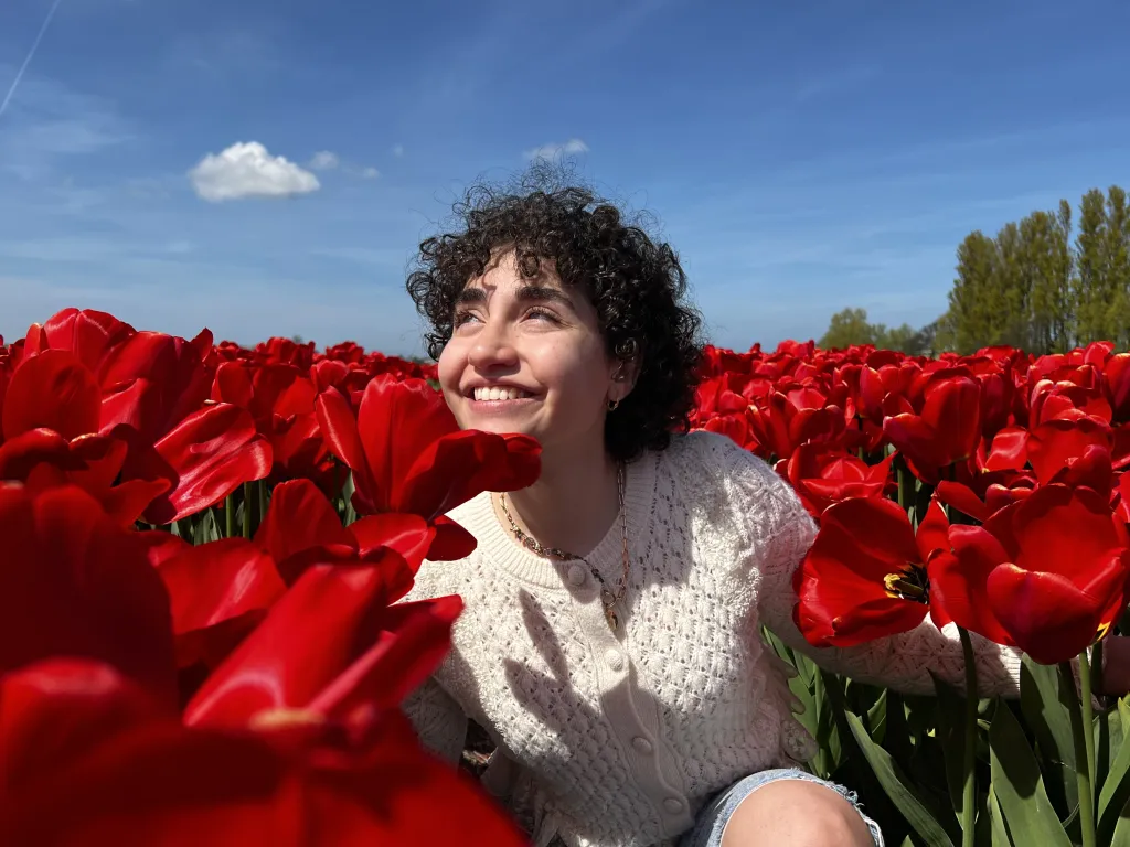 woman crouches in a field of red tulips in the Netherlands