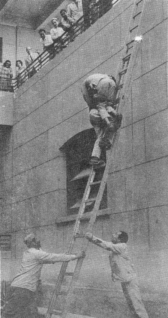 man climbs down a ladder carrying another man