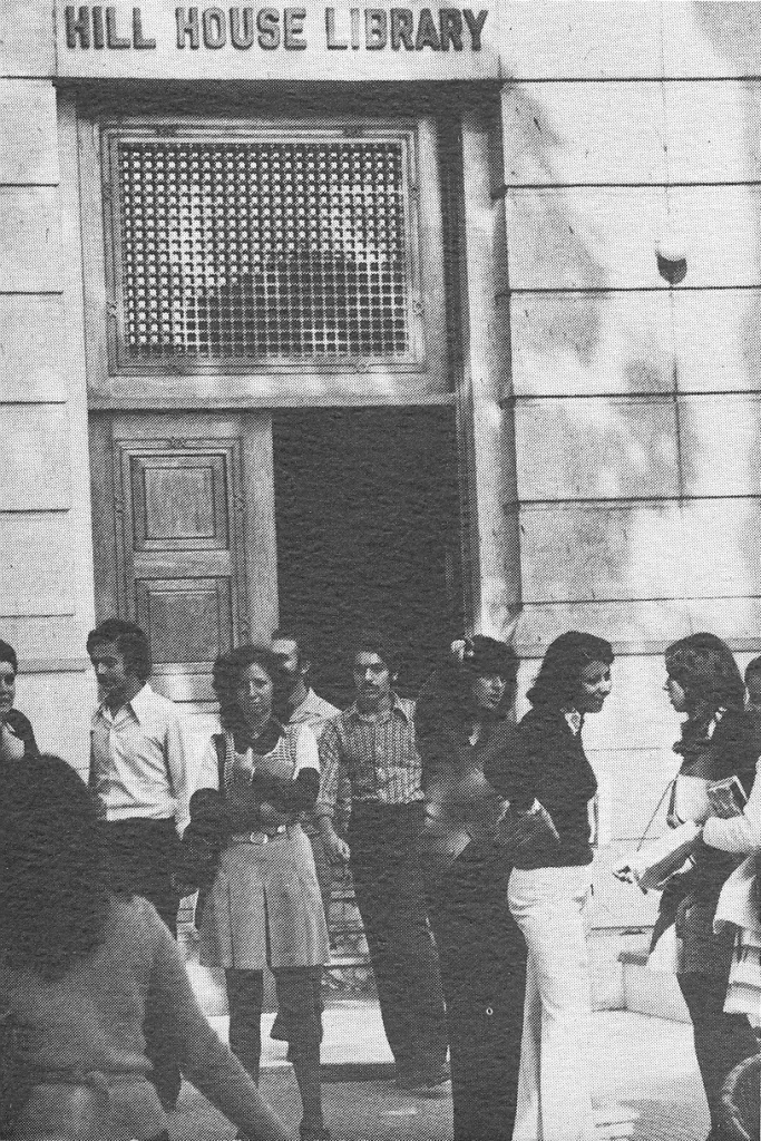 Students standing outside a doorway labeled Hill House Library at AUC Tahrir Square